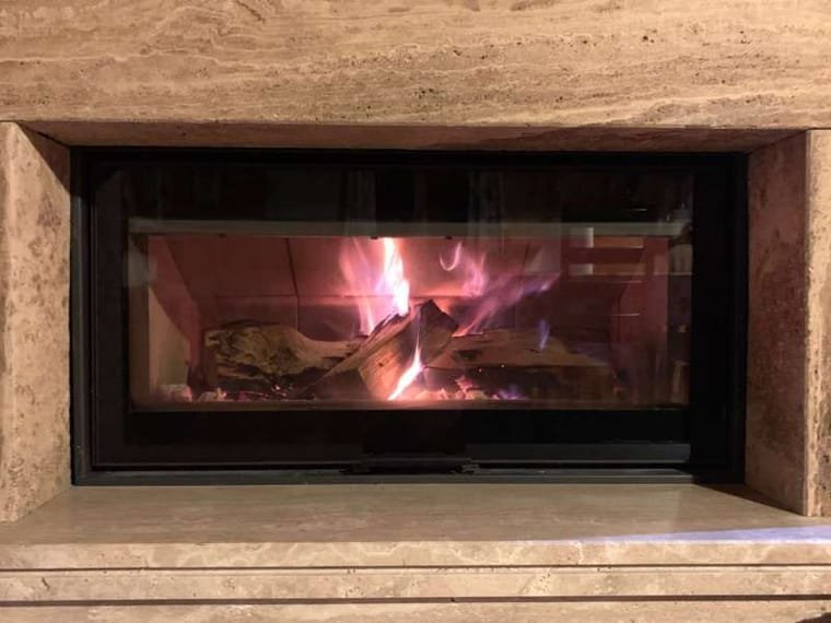 Ložište upaljenog kamina u masivnom travertinskom okviru, snimljeno izbliza, Markvinia Biograd na Moru